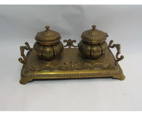 A brass double inkwell on stand, pierced form, bracket style feet 