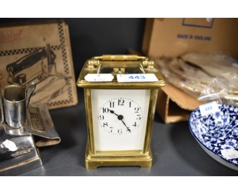 A vintage brass carriage clock having visible escape and enamel face and bevelled glass sides, untested, with key.