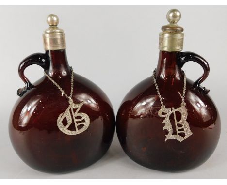A pair of Victorian brown tinted mallet shaped claret jugs, each with silver plated stopper and collar, and a decanter label 