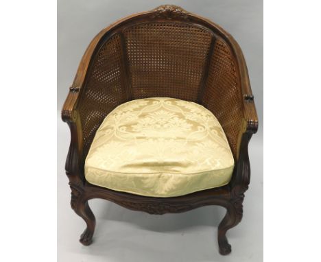 A hardwood bergere type chair, with a moulded and flower carved show frame, caned back and seat, on cabriole legs, with loose