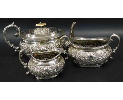 A silver plated three piece tea service, embossed with scrolls etc., the teapot lid with ivory knop