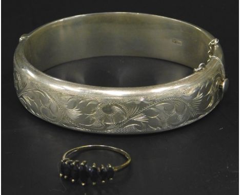 Two items of silver jewellery, to include a florally engraved bangle, and a blue stone set dress ring. 