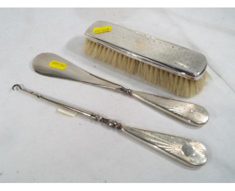 Three pieces of hallmarked silver comprising a clothes brush, a shoe horn and a button hook, various assay marks - Est £20 - 