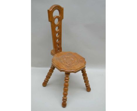 A CARVED OAK SPINNING CHAIR, pierced back, the seat carved with a Tudor rose, raised on four bobbin turned supports, stamped 