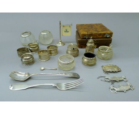 A quantity of various silver and silver-mounted items, including cruets, spoons, napkin rings, decanter labels, etc. The fork