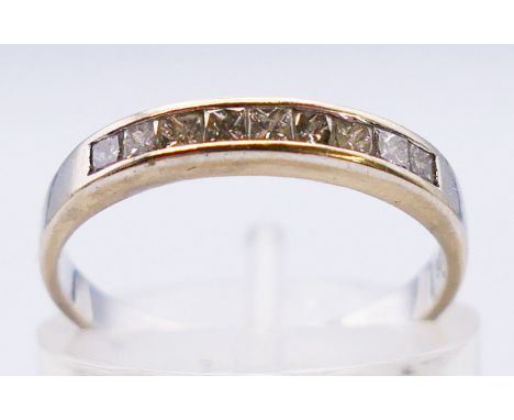 An 18 ct white gold nine stone diamond channel set half eternity ring. Approx 0.25 carat. 1.9 grammes. Ring size K.