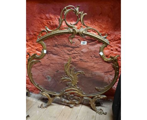 A cast brass and mesh fire screen of Rococo scroll form