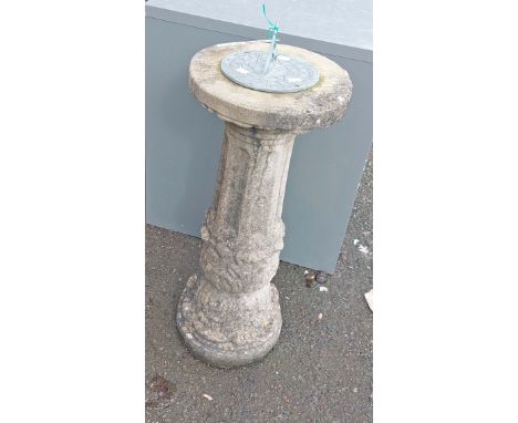 A sundial with text to gnomon, set on a concrete pedestal base