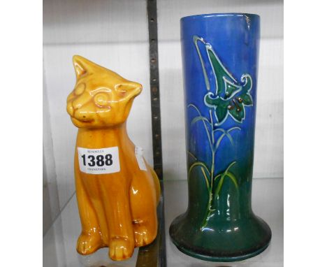 A C.H. Brannam Barnstaple art pottery figurine depicting a seated cat with yellow glaze finish - sold with a cylindrical spil