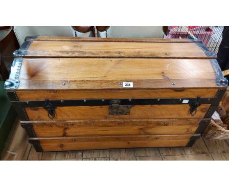 An 84cm late Victorian metal bound waxed pine dome-top travelling trunk with flanking iron drop handles and decorative paper 