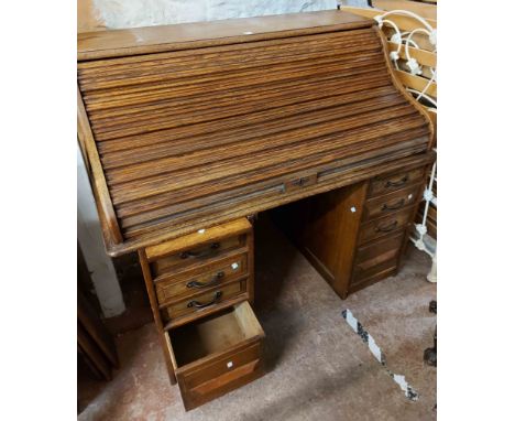 A 1.25m vintage stained oak roll-top desk with part fitted interior and flanking pedestal slides, drawers and deep file drawe