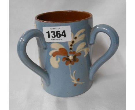 A Torquay pottery tyg with coloured slip decoration on a light blue ground incised with 'W.V.D.H. True Friendship is Everlast