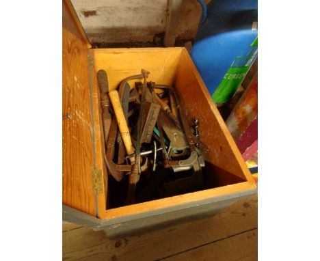 A painted wooden lift-top medicine chest containing a quantity of old hand tools including saws, files, hammers, etc.