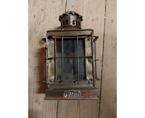 An old brass oil lantern of cage form with glass panes and GWR plaque to front - handle missing