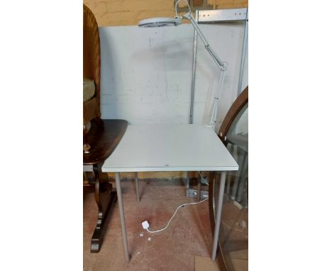 A modern worktable with white melamine finish and attached magnifier lamp