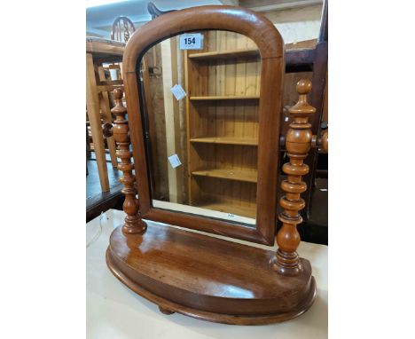 A Victorian mahogany platform dressing table mirror with arch top and flanking bobbin turned supports, set on a bow front bas