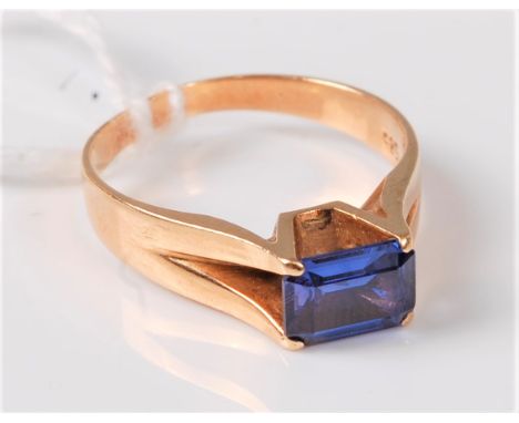 A 14ct synthetic sapphire ring, the pale lavender blue step cut synthetic sapphire, in a four claw mount with split shoulders