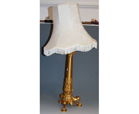 An early 20th century gilt brass table lamp, having acanthus leaf decoration to tripod base with paw feet, having pleated sil