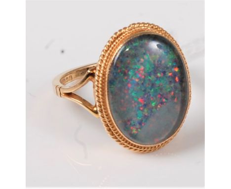 A 9ct opal ring, the oval opal, possibly a doublet, collet mounted with rope twist border, split shoulder and plain band hall