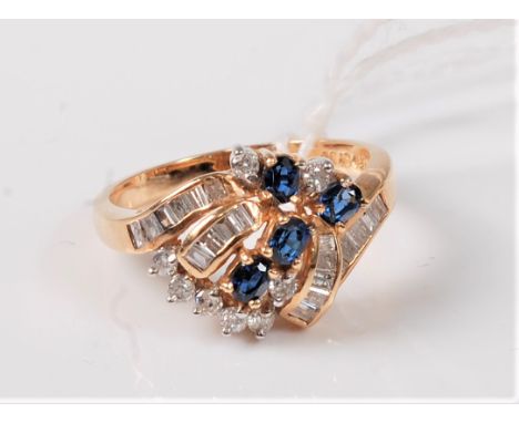 A sapphire and diamond cluster ring, the oval sapphires set among a folding ribbon of channel step cut diamonds and small rou