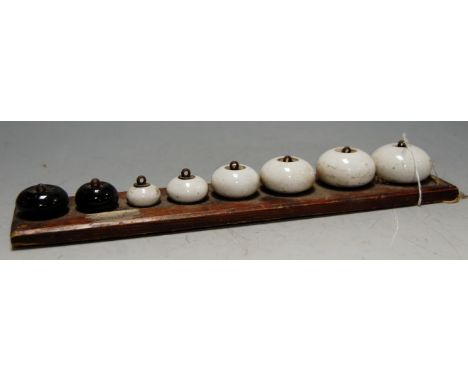 A collection of eight various ceramic servants bells mounted on pine board