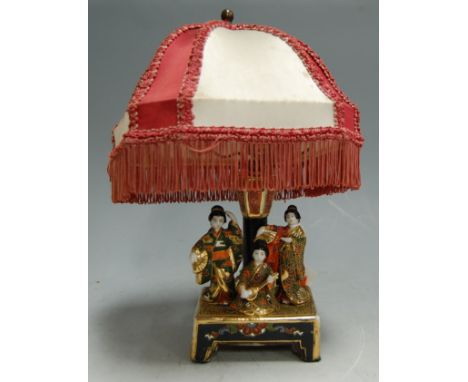 A Japanese Taisho period lamp base surmounted by three figures, with silk shade