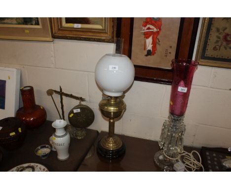 A brass oil lamp with milk glass shade and glass chimney