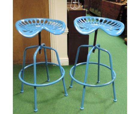 A pair of blue painted metal tractor seat bar stools