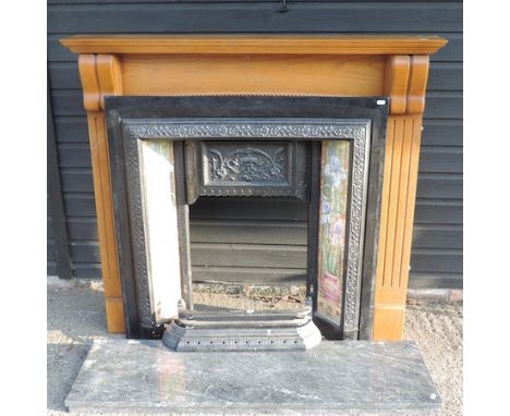 A black painted cast iron and tiled fire insert, with a pine surround, 126 x 117cm