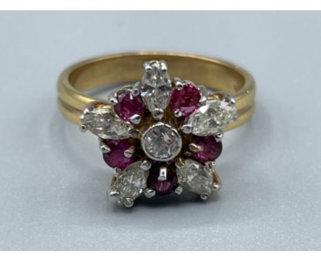 Ladies 18ct gold Ruby and Diamond cluster ring. Comprising of a Round brilliant cut diamond in centre surrounded by 5 round c