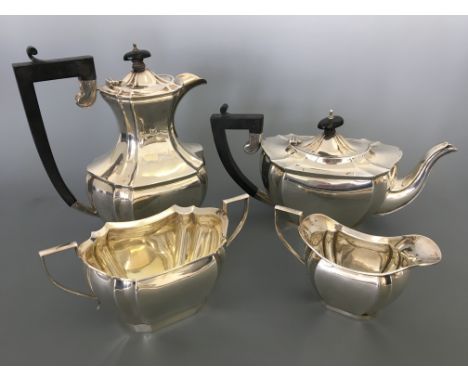 A silver four piece tea set consisting of a tea pot with ebony handle and finial, similar hot water jug, twin handled sugar b