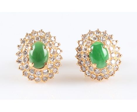 A pair of green jadeite jade and diamond cluster earrings, each set with an oval jadeite cabochon surrounded by two rows of e