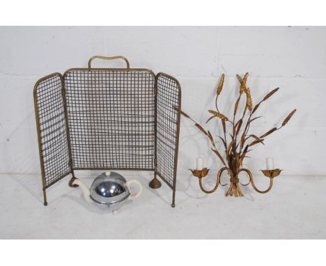 A decorative gilded wall light fitting, along with a brass fire guard and a retro tea pot