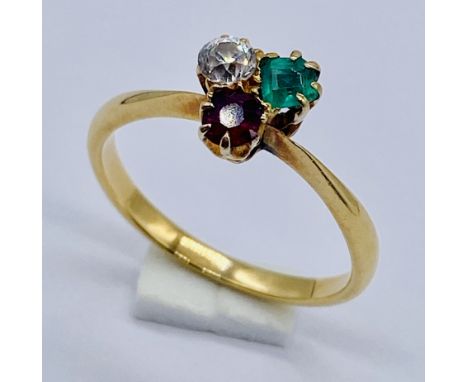 An unmarked 9ct gold three stone ring set with a diamond, emerald and a ruby