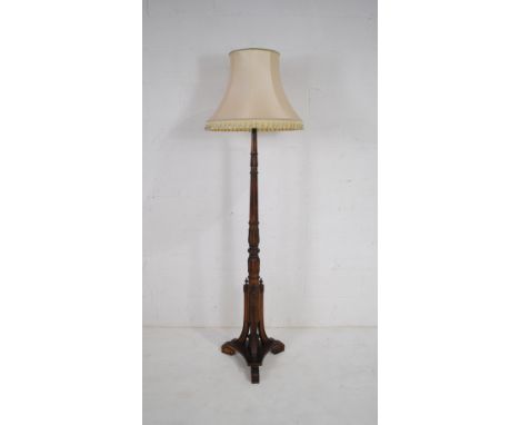An antique standard lamp, with tripod supports and carved detailing