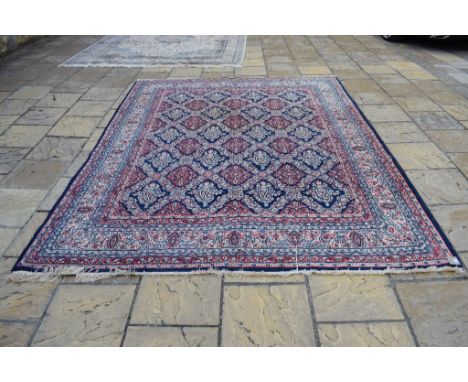 A Persian Tehran carpet, with repeating floral motifs on a blue ground, within a multi border, 343 x 266 cm