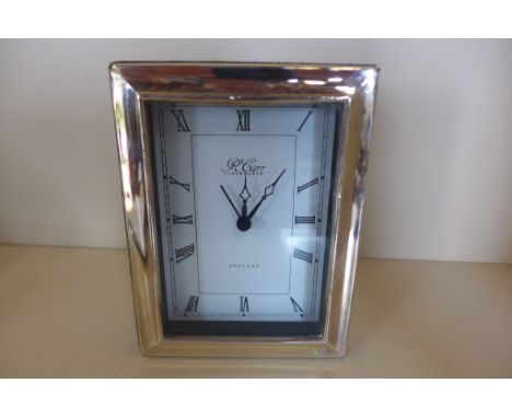 A silver framed Quartz alarm clock by R Carr 15x12cm - running, minor dents 
