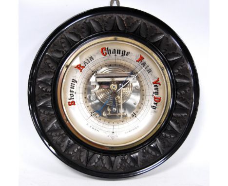 Edwardian carved oak and glass aneroid barometer, retailed by Edward Ewen of Dumfries, 34cm diameter.