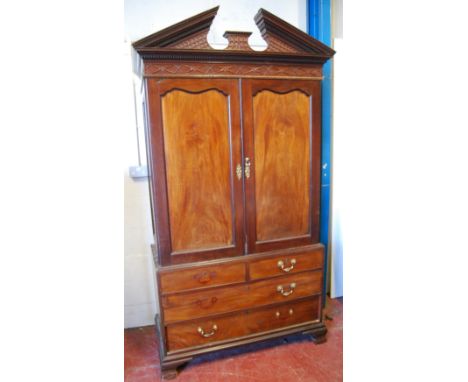 Mahogany linen press with fret-carved frieze, two cupboards enclosing linen slides and three drawers below, on bracket feet, 