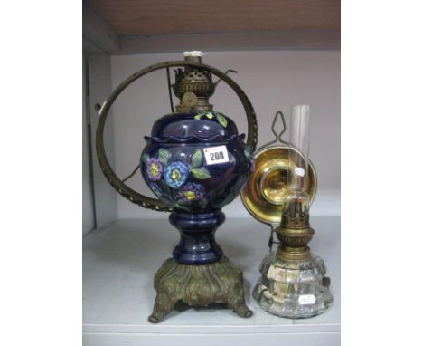 A Continental Ceramic Oil Lamp, with floral body and metal base (fitting damage), and a glass well chamber lamp with brass re