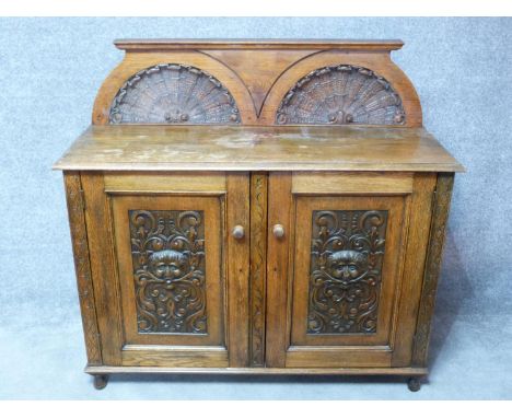 A 19th century oak side cabinet with shell carved superstructure above carved panel doors enclosing shelves. H.125 W.132 D.49