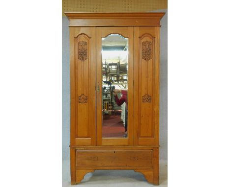 A late 19th century satin walnut wardrobe with central shaped bevelled mirror door flanked by Art Nouveau inspired carved pan