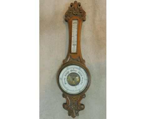 A late 19th century carved oak aneroid barometer with mercury thermometer. 90x25cm 