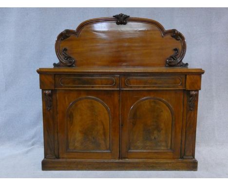 A Victorian flame mahogany chiffonier with shaped and carved back above pair of frieze drawers above arched panel doors enclo