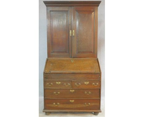 A Georgian country oak bureau bookcase with upper section fitted with fielded panel doors enclosing drawers and pigeon hole s