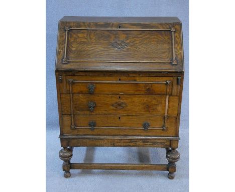 A mid century vintage oak bureau in the Jacobean style with fall front revealing fitted interior on bulbous turned stretchere