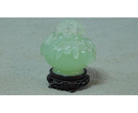 A 20th century serpentine jade lidded censer on a footed pierced carved hardwood base. The censer is carved with leaves and p