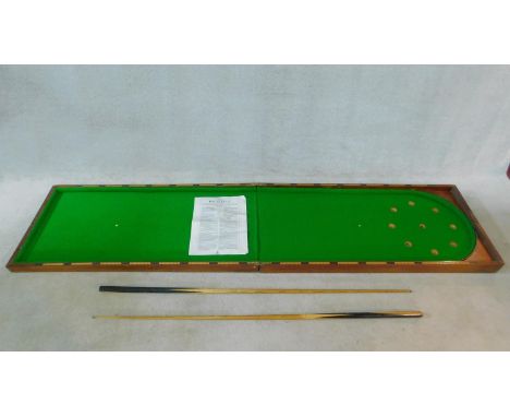 A vintage folding table top bagatelle table in mahogany case lined with green baize, with two cues and rules guide. 