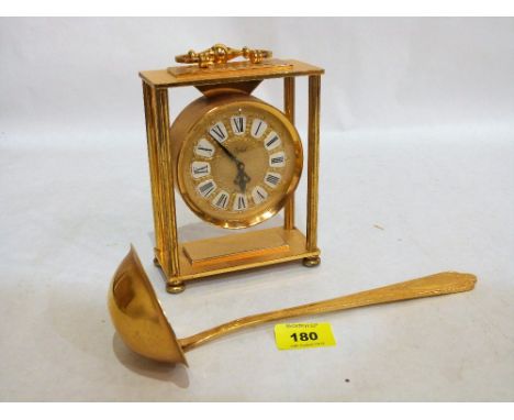 A German gilt plated mantle clock with jewelled movement, 6'' high and a gilt plated ladle