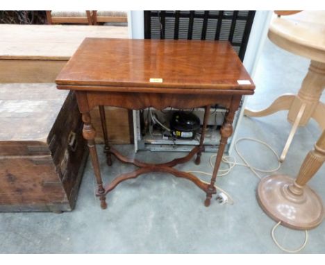 An early 20th century walnut card table, the quarter veneered and crossbanded fold-over top on knopped slender legs united by